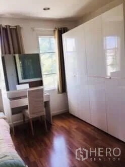 Townhouse for rent in Bang Kapi, Bangkok - Bedroom corner with glossy white wardrobe, dressing table and curtained window.