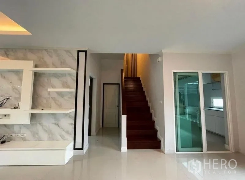 บ้าน ขายในBang Phli, Samut Prakan - บันไดไม้ข้างประตูกระจกบานเลื่อนไปยังครัวแยกและโถงทางเดิน