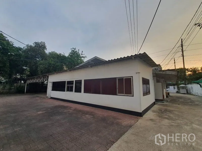Home Office for rent in Watthana, Bangkok - Single‑storey annex building with long windows and paved yard