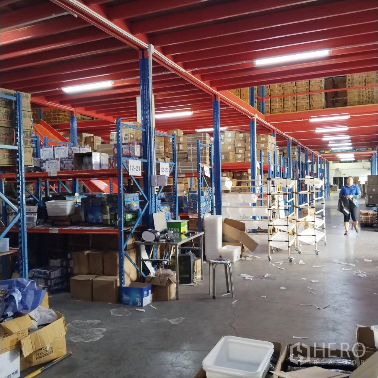 Warehouse for rent in Bang Khun Thian, Bangkok - Storage area with racks, packing tables, and rolling carts.
