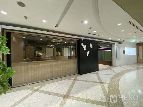 Retail Space for rent - Alternative view of the closed glass shopfront with recessed ceiling lights in the mall.