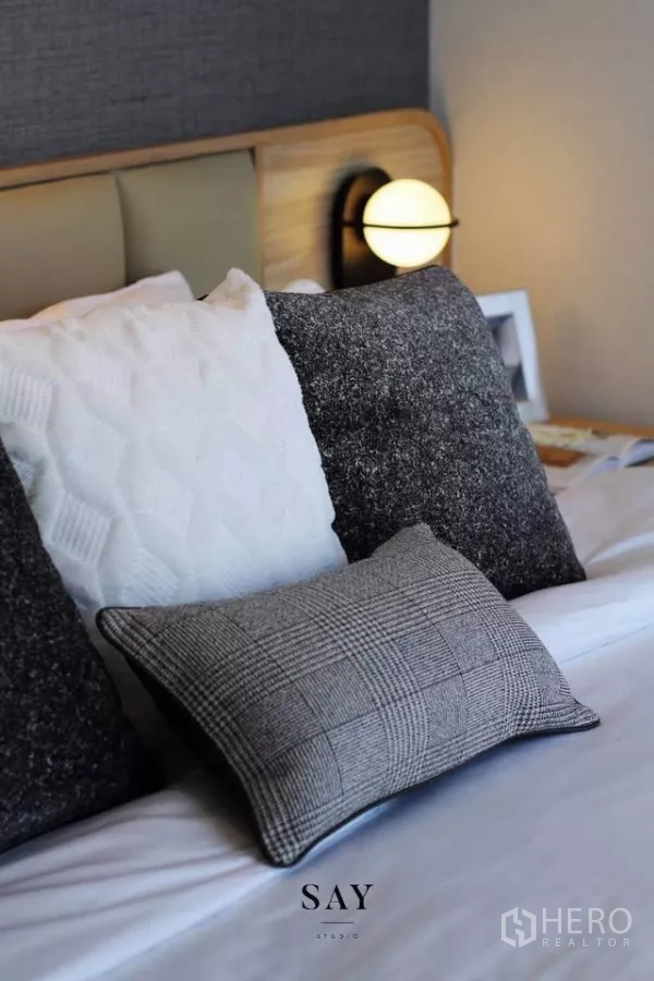 Condominium for rent or sale in Khlong Toei, Bangkok - Detail of textured pillows on the bed with a bedside sconce.