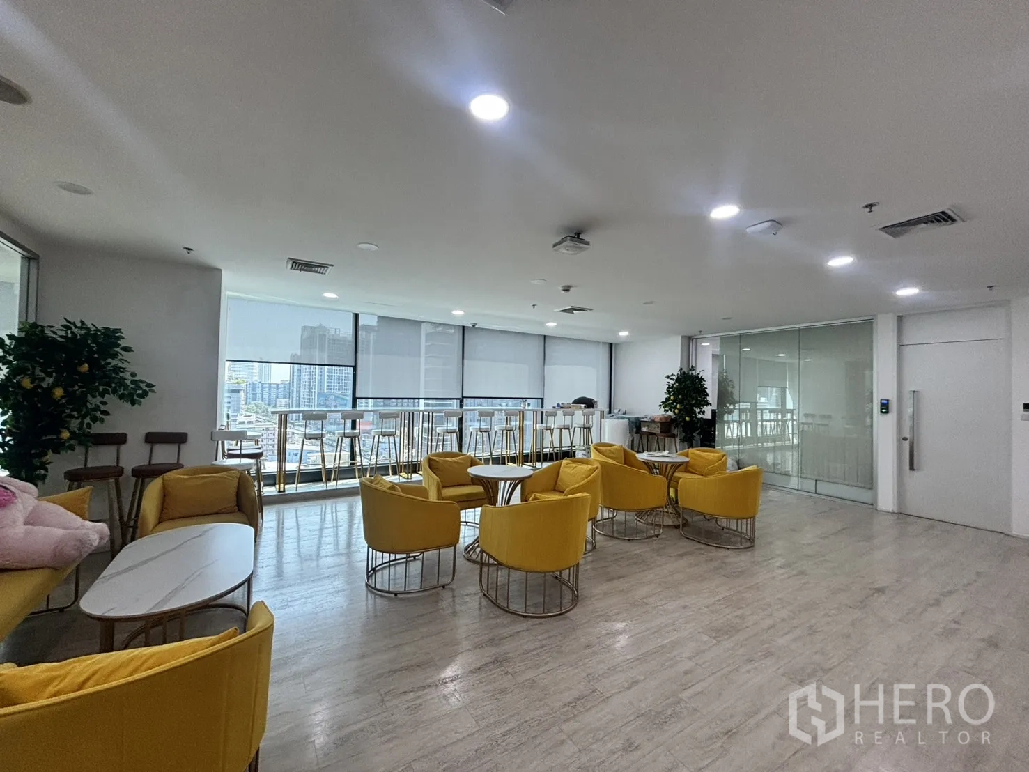 Office Space for rent in Din Daeng, Bangkok - Staff lounge with yellow armchairs, bar seating by picture windows and city views.