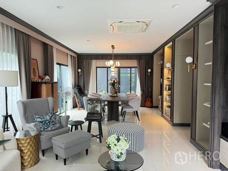 Detached House for rent in Bang Kapi, Bangkok - Open‑plan living and dining room with built‑in cabinetry, chandelier lighting and cassette air‑conditioning.