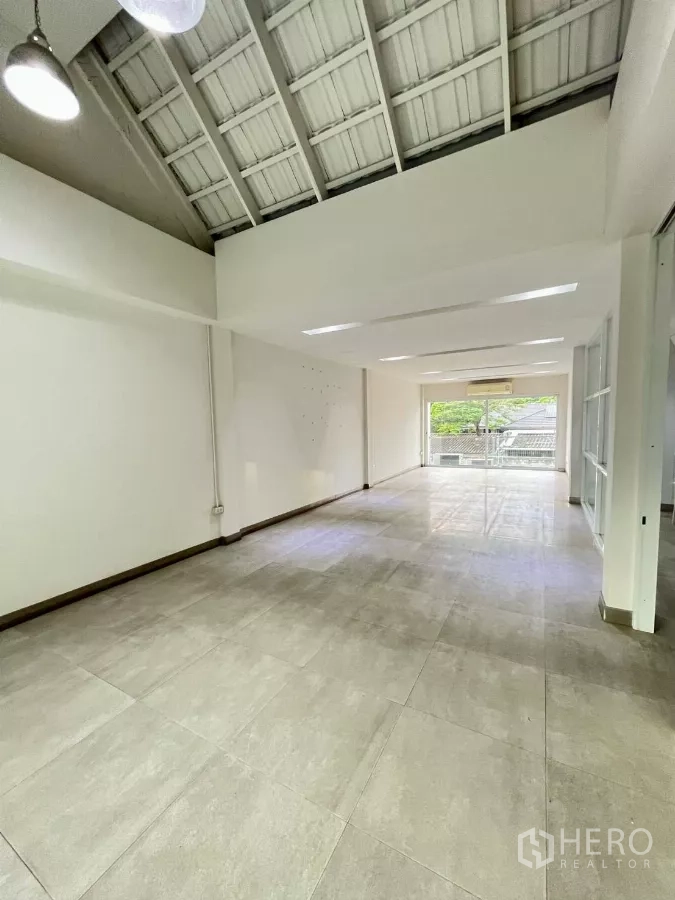 Home Office for rent in Khlong Toei, Bangkok - High-ceiling showroom or office floor with large tiles and sliding doors to balcony.