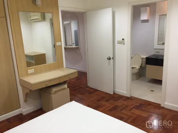 公寓 出租在Watthana, Bangkok - 卧室设梳妆台、衣柜及套内卫浴入口，铺木地板。