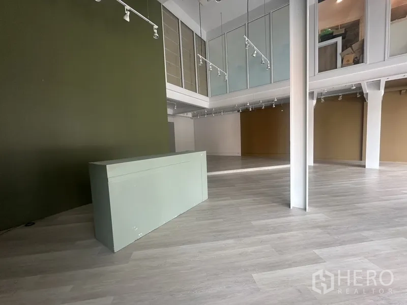 Retail Space for rent in Khlong Toei, Bangkok - Reception or cashier zone with green feature wall, mezzanine glazing and open ceiling.