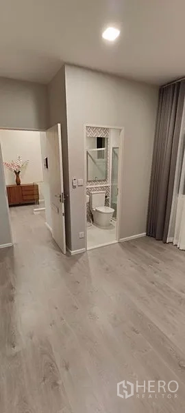 Detached House for rent in Prawet, Bangkok - En-suite bathroom with glass shower seen from the bedroom entrance.