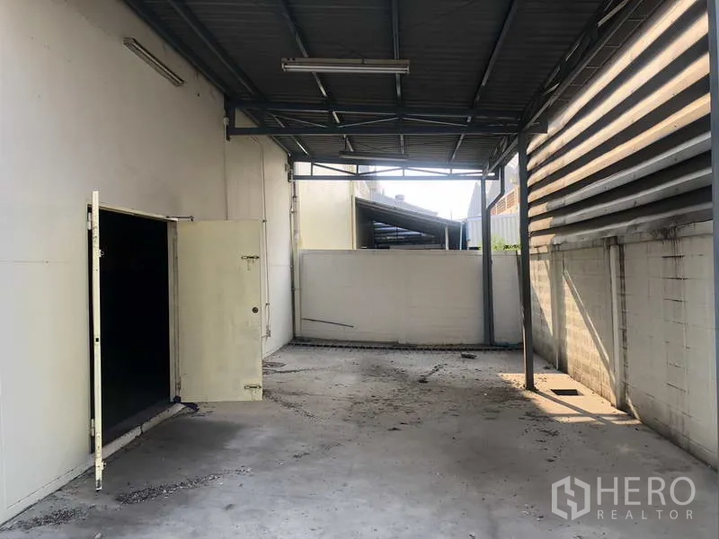 工厂 出租在Khlong Luang, Pathum Thani - 带金属顶棚的装卸区，混凝土地面与侧门通道。