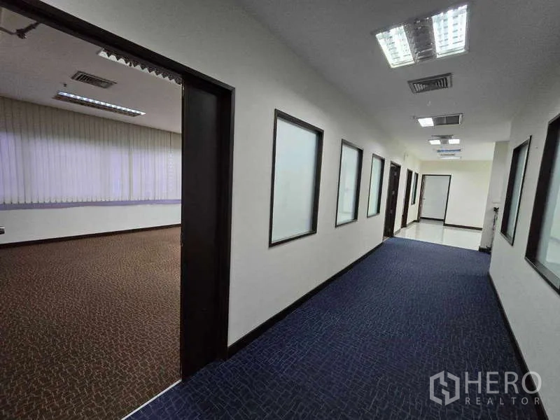 Office Space for rent in Khlong Toei, Bangkok - Hallway with internal windows leading to private rooms in the office suite.