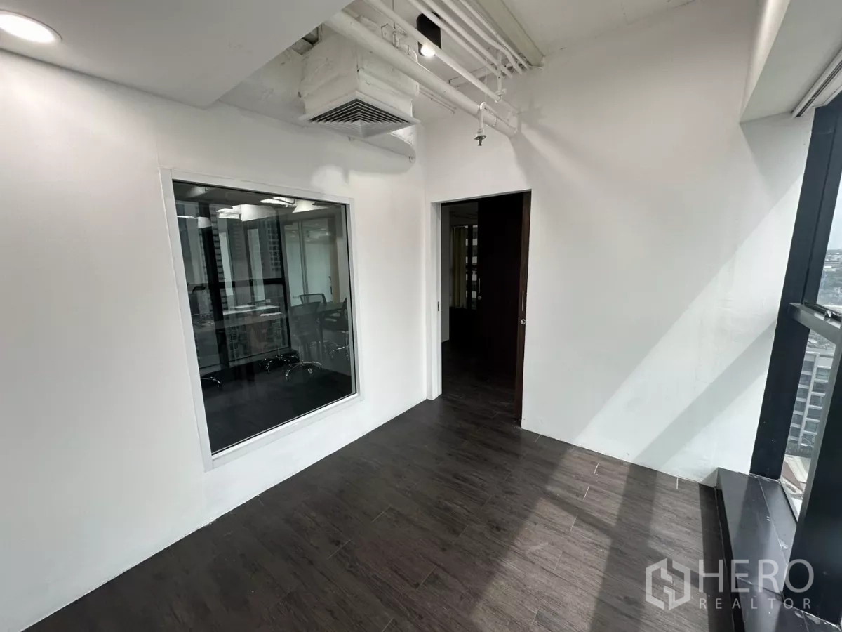 Office Space for rent in Watthana, Bangkok - Small office with interior window, exposed ductwork and a large exterior window.