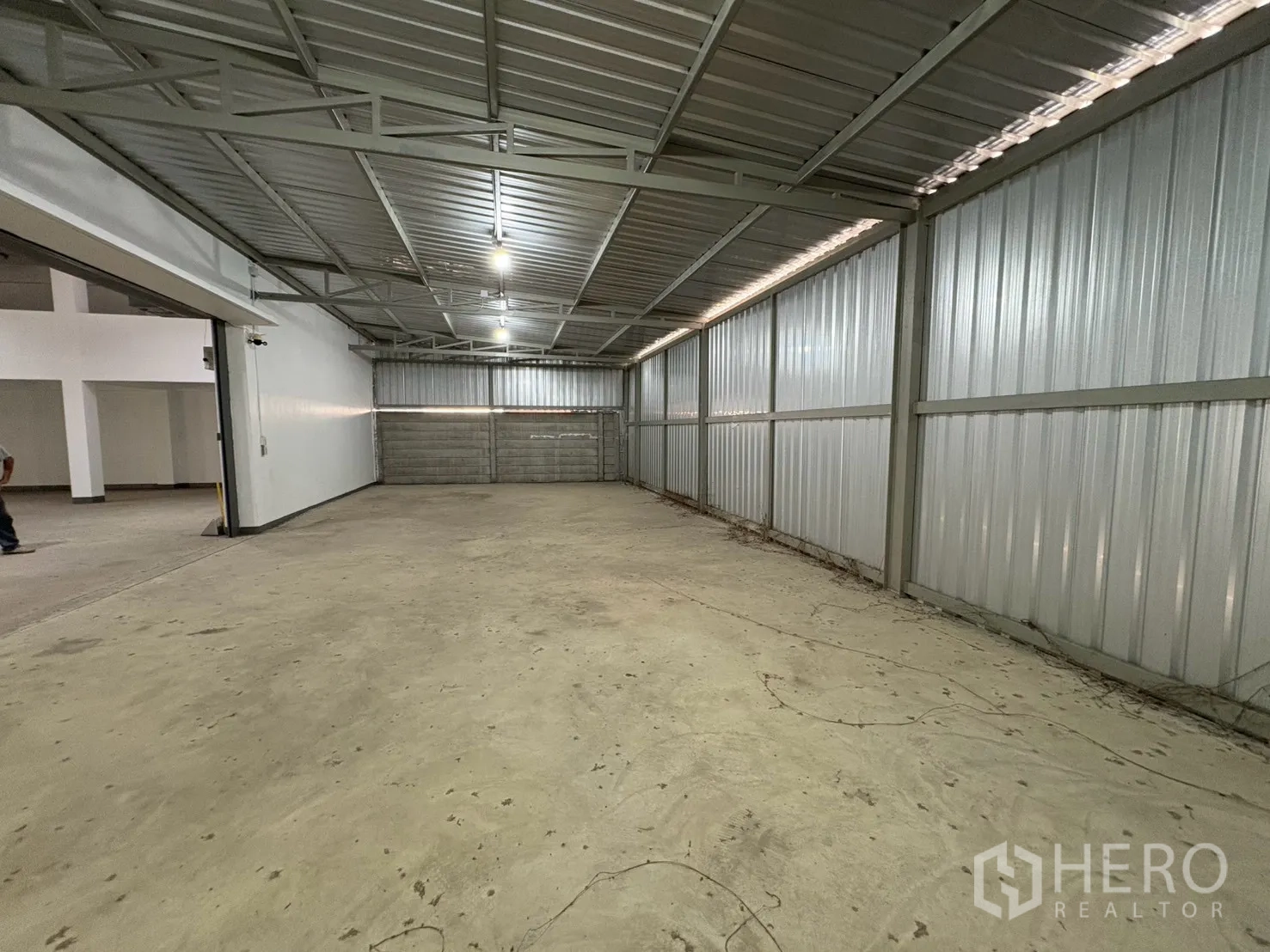 Warehouse for rent in Bang Na, Bangkok - Enclosed metal-clad storage room with a partially closed roller door.