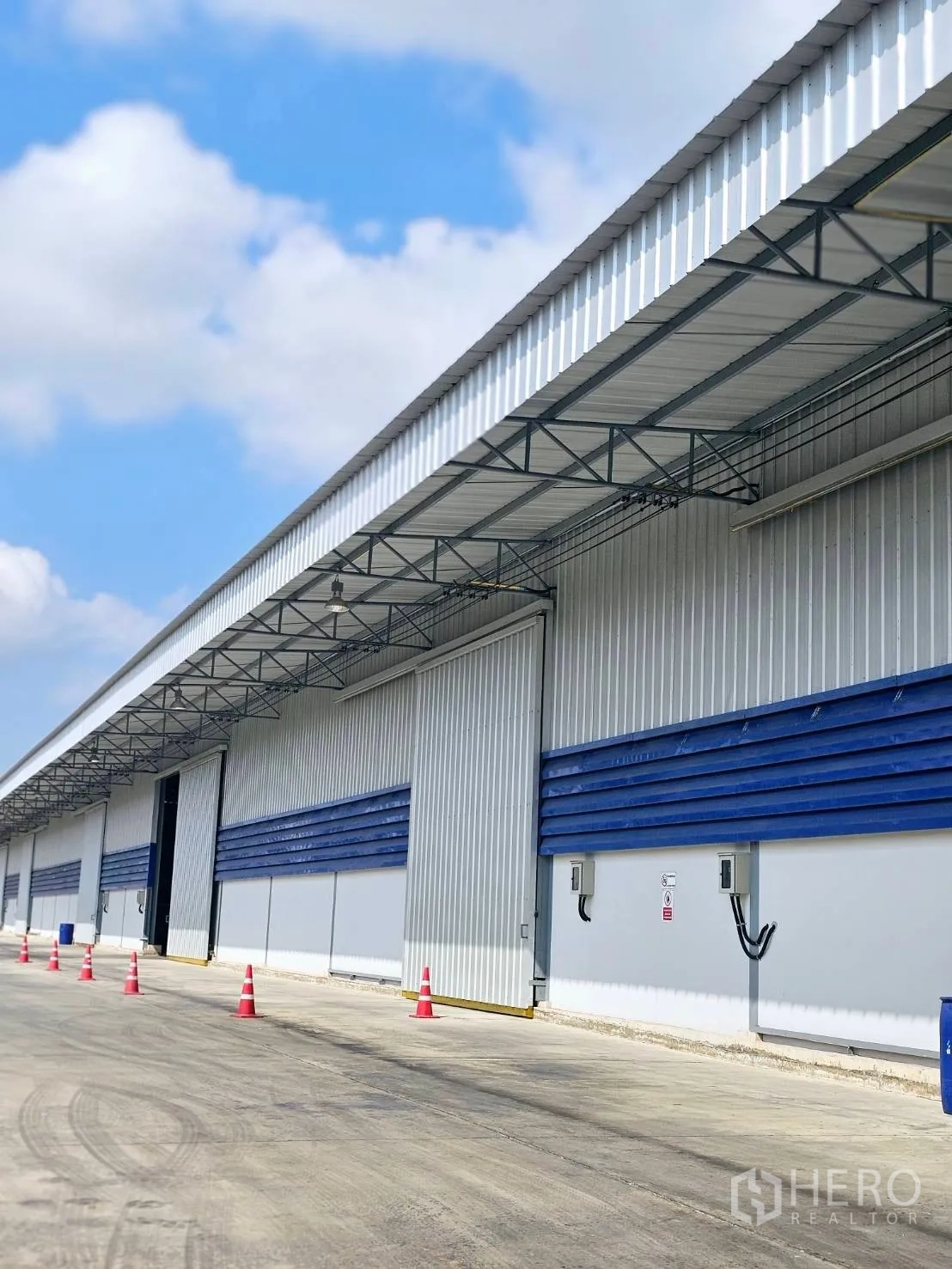 Warehouse for rent in Lat Krabang, Bangkok - Warehouse exterior with metal cladding, sliding doors, covered loading bay, and a wide driveway.