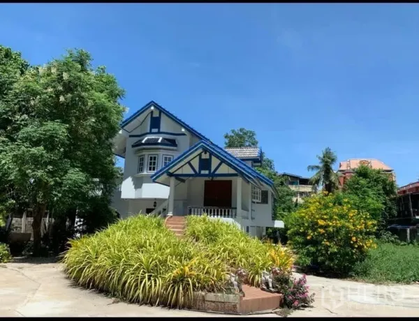 独立式住宅 出租在Khlong San, Bangkok - 白天正立面，蓝色屋顶的山墙式住宅与郁郁花园
