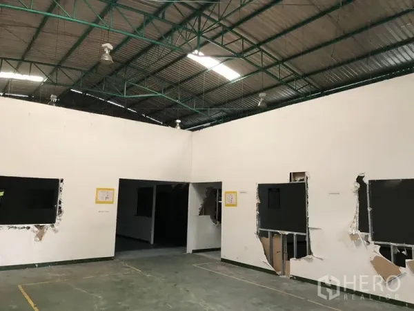 Factory for rent in Pathum Thani - Factory interior showing high steel-truss ceiling, partitioned rooms and solid concrete floor.