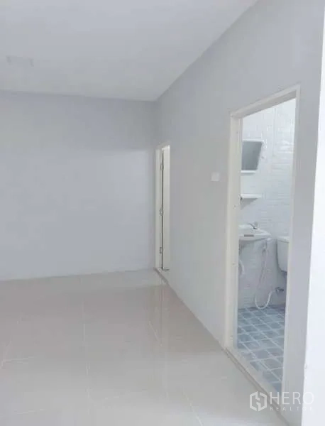 货栈 出租在Pathum Thani - 通往仓内卫生间的小过道，卫生间铺砖并配有洗手盆与马桶。