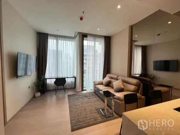 Condominium for rent - Open-plan living area with TV, sofa, rug and balcony door letting in soft daylight through sheer curtains.