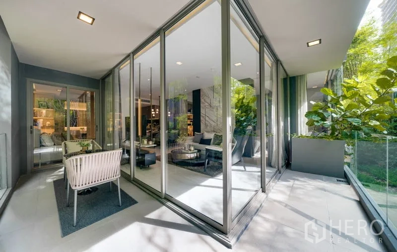 Condominium for rent in Watthana, Bangkok - Corner balcony with sliding glass walls, greenery, and outdoor seating.