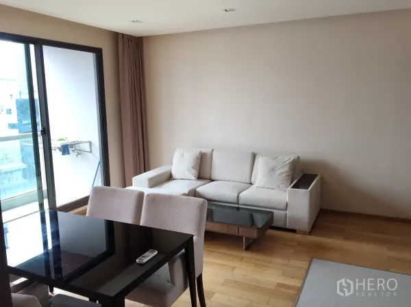 Condominium for rent in Bang Rak, Bangkok - Bright lounge with beige sofa, glass coffee table and sliding doors opening to the balcony.