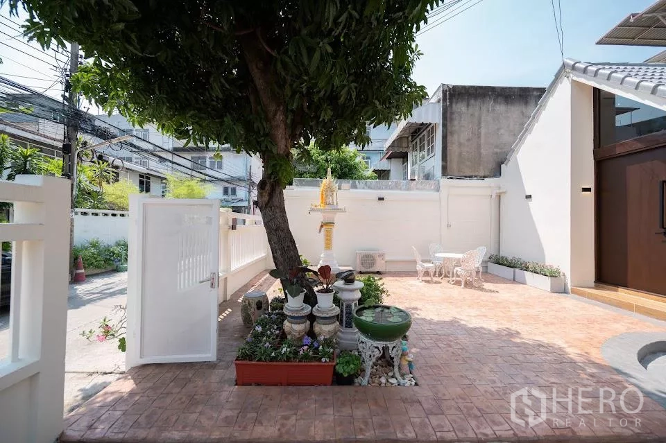 Detached House for rent in Phra Khanong, Bangkok - Front courtyard with shady tree, small shrine, planters and gate to the street.