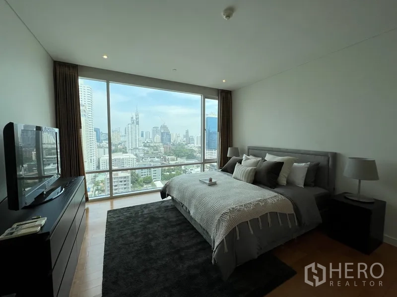 Condominium for rent in Watthana, Bangkok - Master bedroom with king bed and floor-to-ceiling windows overlooking Bangkok.
