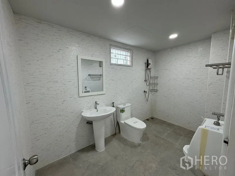 Home Office for rent in Bueng Kum, Bangkok - Modern bathroom with shower, toilet and pedestal sink under a small window.