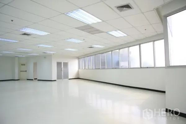 Office Space for rent in Chatuchak, Bangkok - Open workspace with polished floors, frosted windows, exit doors, and suspended ceiling.