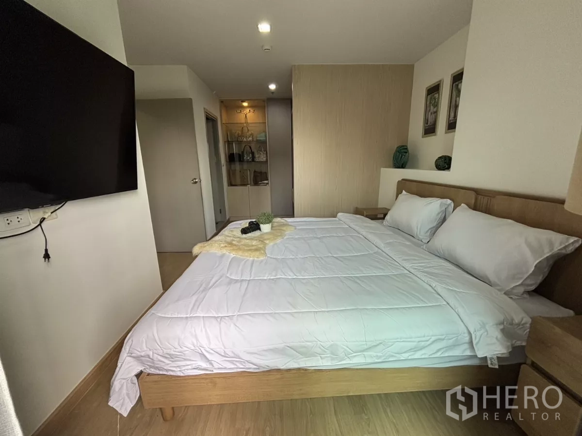 公寓 出租在Phra Khanong, Bangkok - 卧室配大电视与床头柜，灯光温馨。