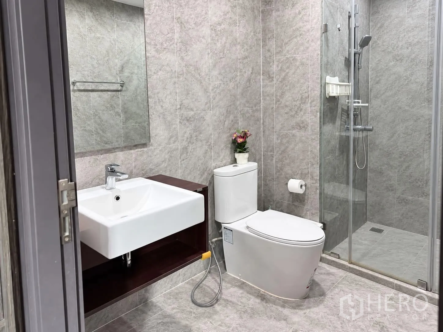Condominium for rent in Watthana, Bangkok - Modern bathroom with wall tiles, glass-enclosed shower, vanity, and toilet.