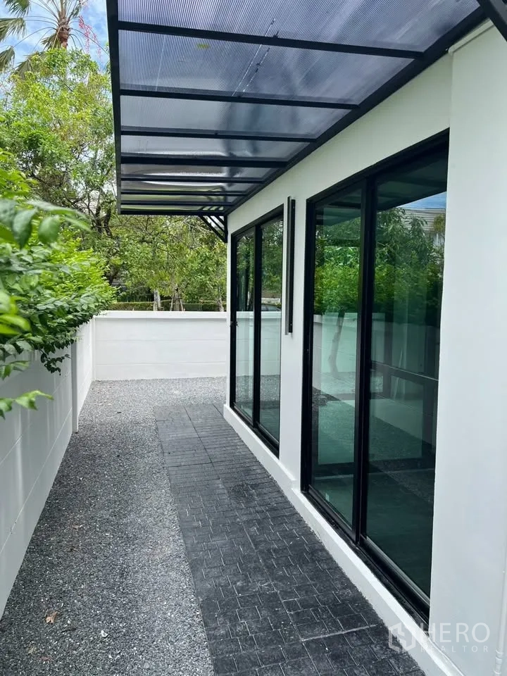 联排别墅 for rent in Prawet, Bangkok - 侧院有顶露台，推拉玻璃门与碎石小径。