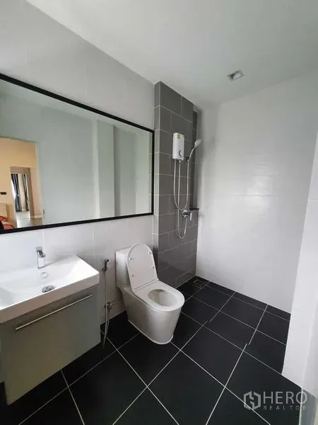 Detached House for rent in Khlong Luang, Pathum Thani - Modern bathroom with large mirror, wall-mounted shower and black floor tiles.