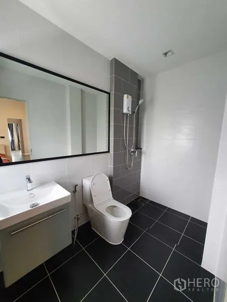 Detached House for rent in Khlong Luang, Pathum Thani - Modern bathroom with large mirror, wall-mounted shower and black floor tiles.