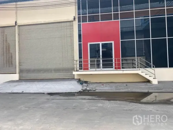 Factory for rent in Bang Phli, Samut Prakan - Factory frontage with large roller shutter, glass entry and red facade panel.