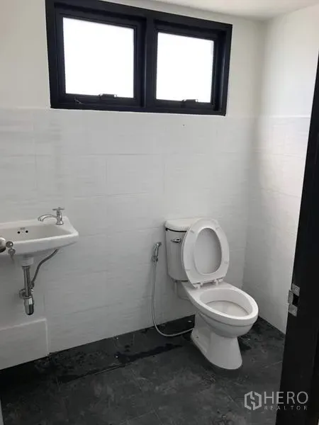 Factory for rent or sale in Lam Luk Ka, Pathum Thani - Clean restroom with white wall tiles, toilet, sink, and small ventilated windows.