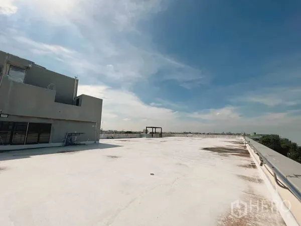 Retail Space for rent in Yan Nawa, Bangkok - Expansive white-coated rooftop deck with building core and safety railing under blue sky in Yan Nawa, Bangkok.