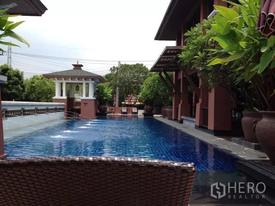 Detached House for sale in Bang Phli, Samut Prakan - Estate swimming pool with pavilion, deck seating and tropical plants.