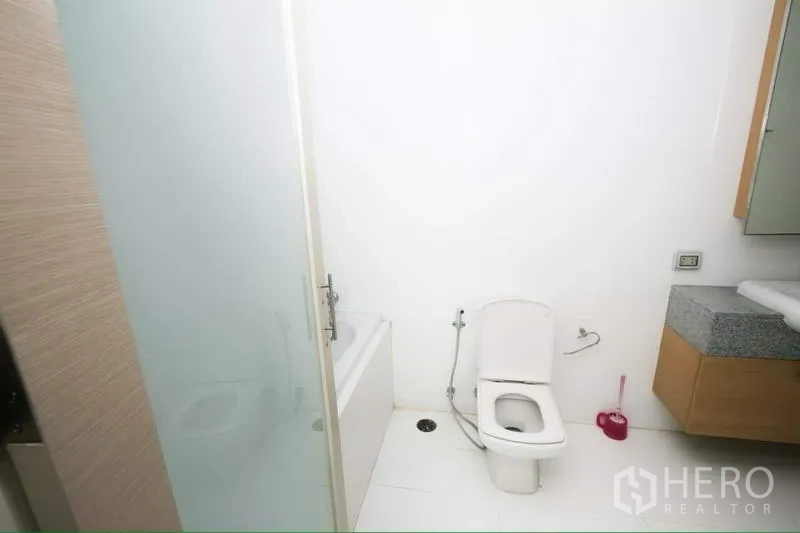 Condominium for rent in Ratchathewi, Bangkok - Clean bathroom with bathtub, glass partition, toilet and vanity.