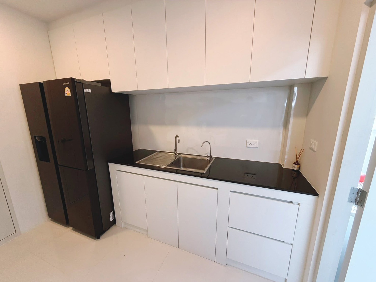 Detached House for rent in Bang Phli, Samut Prakan - Secondary kitchen counter with sink, white cabinets and a tall refrigerator.