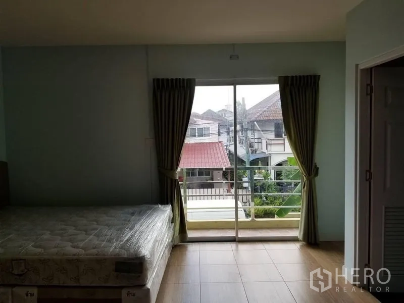 Townhouse for rent in Bang Kapi, Bangkok - Master bedroom with sliding glass doors to a small balcony overlooking the neighborhood.