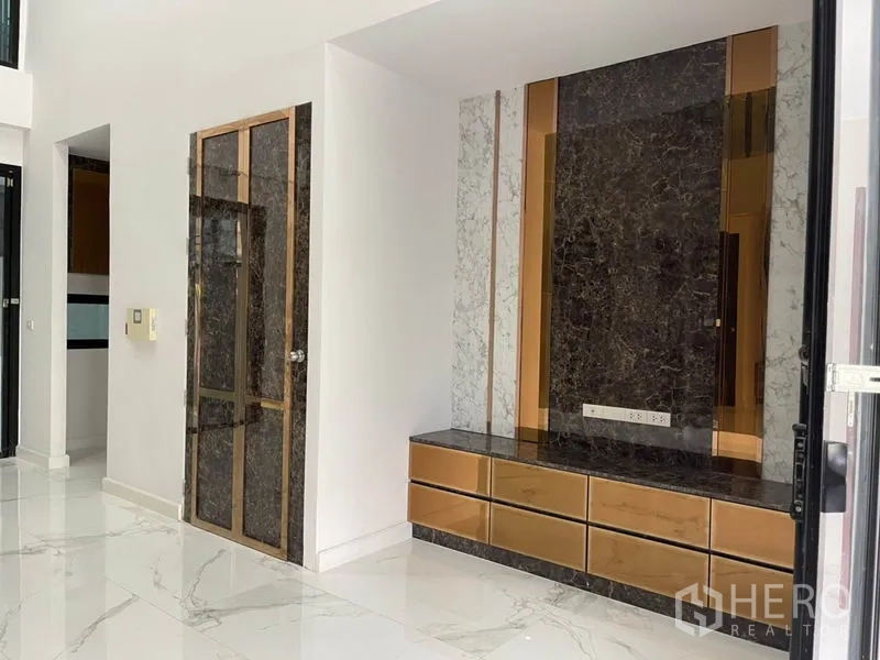 Townhouse for rent or sale in Yan Nawa, Bangkok - Built-in TV wall with marble slab, bronze drawers, and shiny white floor.