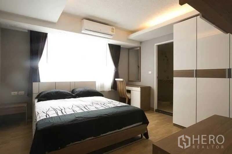 Condominium for rent in Khlong Toei, Bangkok - Bedroom with double bed, desk, wardrobe and en-suite door, filled with natural light.