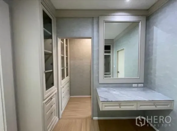 Townhouse for sale - Dressing area featuring a marble-top vanity, large mirror, and glass-front wardrobes.