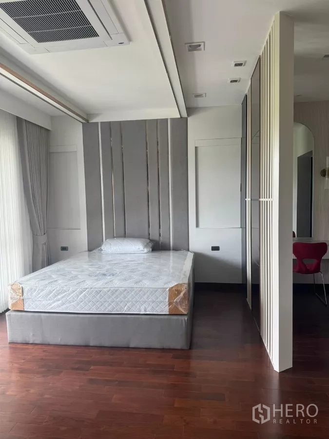 Detached House for rent in Lat Krabang, Bangkok - Spacious bedroom with paneled headboard, wood flooring and ceiling cassette air-conditioner.