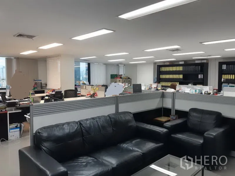 Office Space for sale in Khlong Toei, Bangkok - Reception lounge with black leather sofas beside shared workstations and storage shelves.