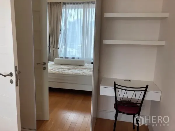 Condominium for rent or sale in Khlong Toei, Bangkok - Compact study nook with wall shelves and a doorway leading to a bedroom with large windows.
