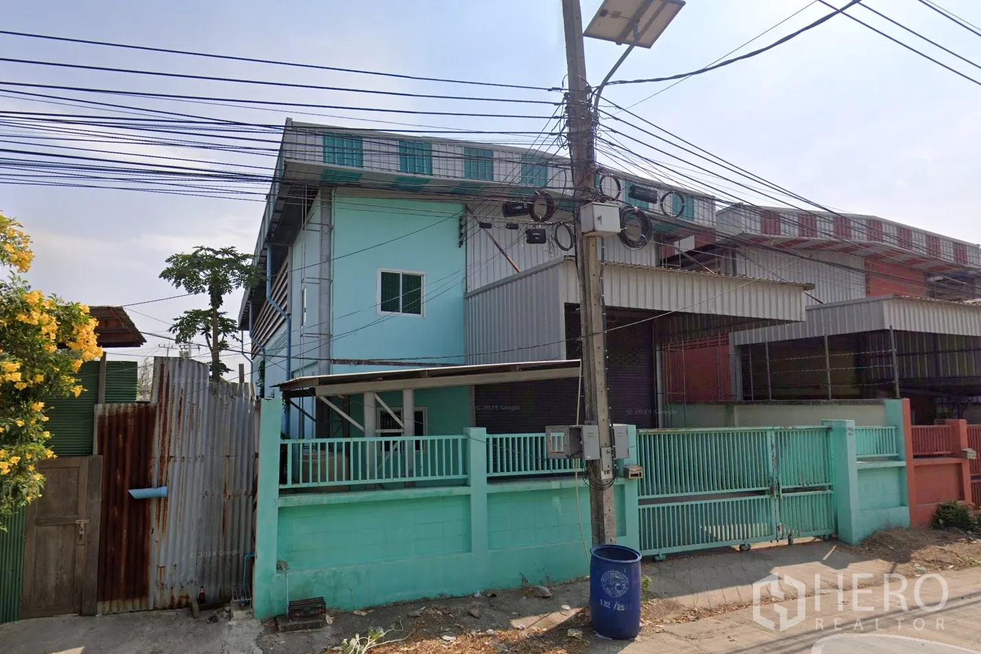 Warehouse for rent in Pak Kret, Nonthaburi - Front view of the building facade and perimeter fence from the street.