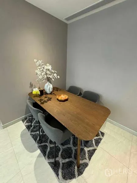 Condominium for rent in Bang Rak, Bangkok - Dining nook with wooden table and four upholstered chairs on a patterned rug
