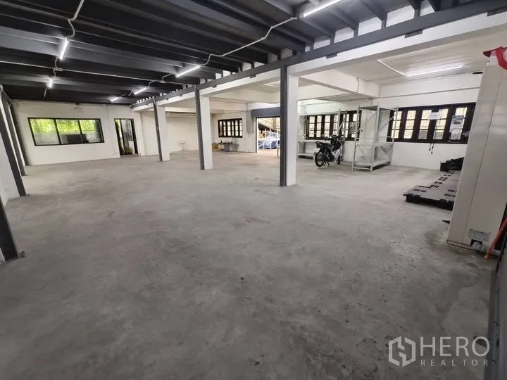 仓库 for rent in Prawet, Bangkok - 仓库内部大开间，混凝土地面，钢柱与长条照明及多扇窗户。