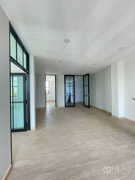 带办公室的家 出租在Bang Kapi, Bangkok - 办公走廊区域，配多扇黑框玻璃门与木地面。