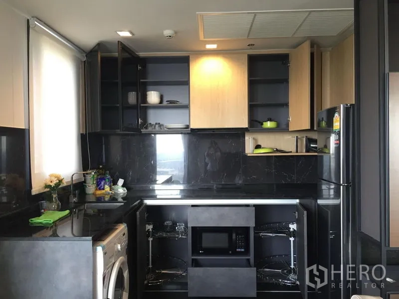 公寓 出租在Chatuchak, Bangkok - 现代U型厨房，黑色石材台面，开放式橱柜，内置微波炉和冰箱。